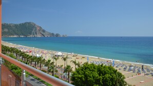 Una spiaggia con palme, ombrelloni e una vista limpida sull'oceano.