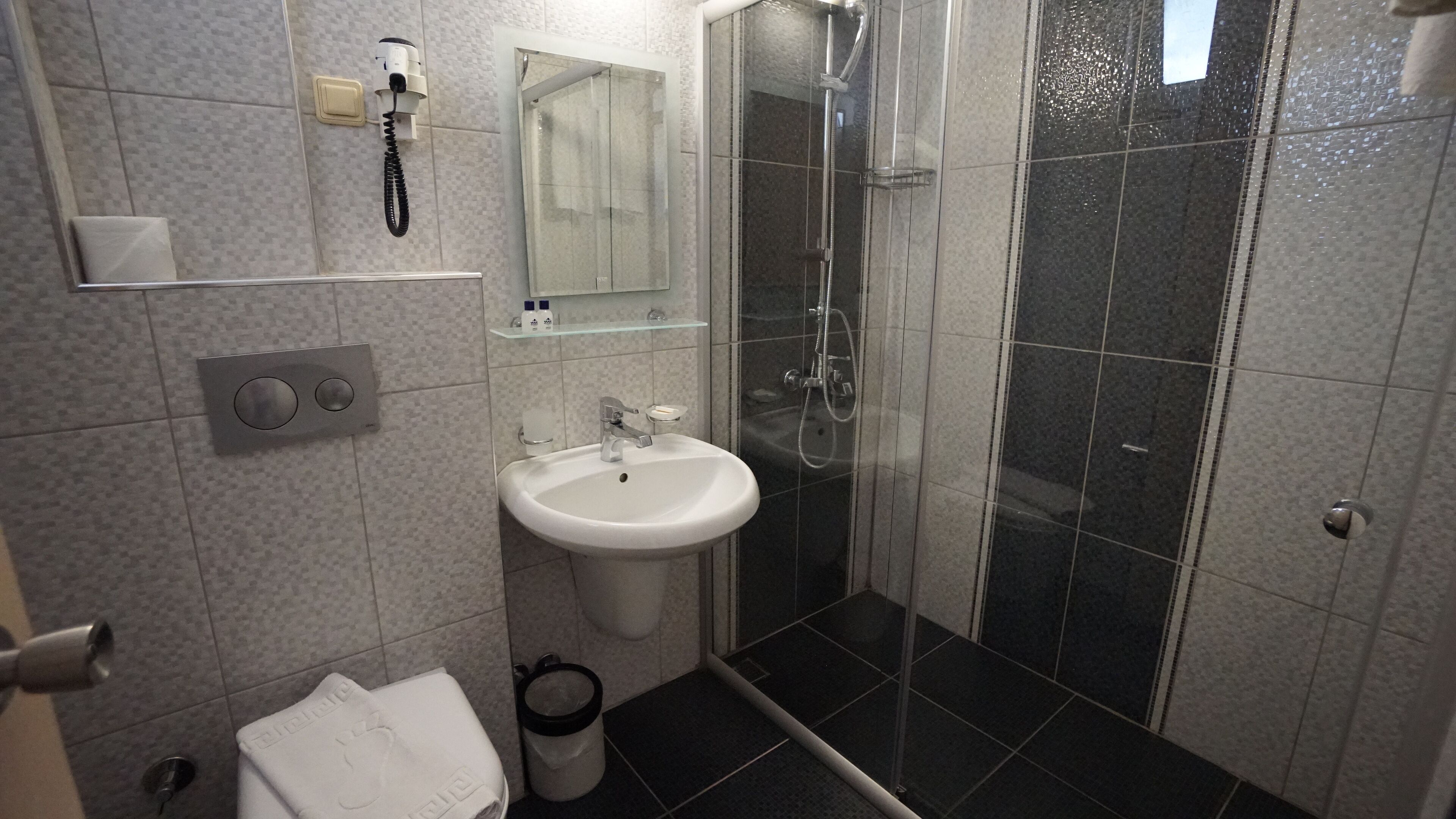 Een badkamer met een witte wastafel, een douchecabine van glas en een handdoekrek.