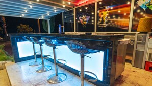 A bar area with a modern design, featuring a bar counter and three high stools. - Kleopatra Celine Hotel (Alanya)
