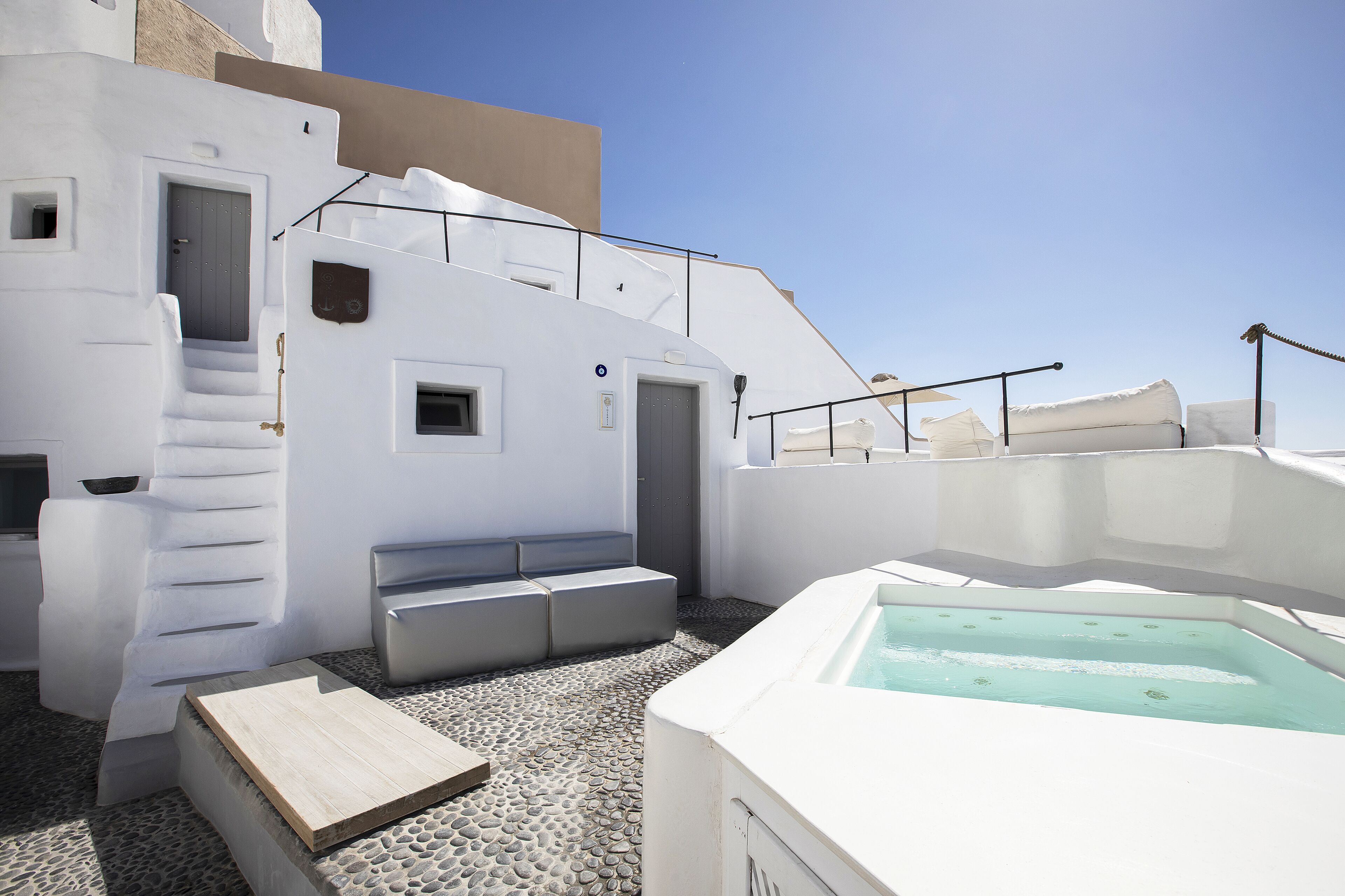 A white building with a pool, steps, and a bench.