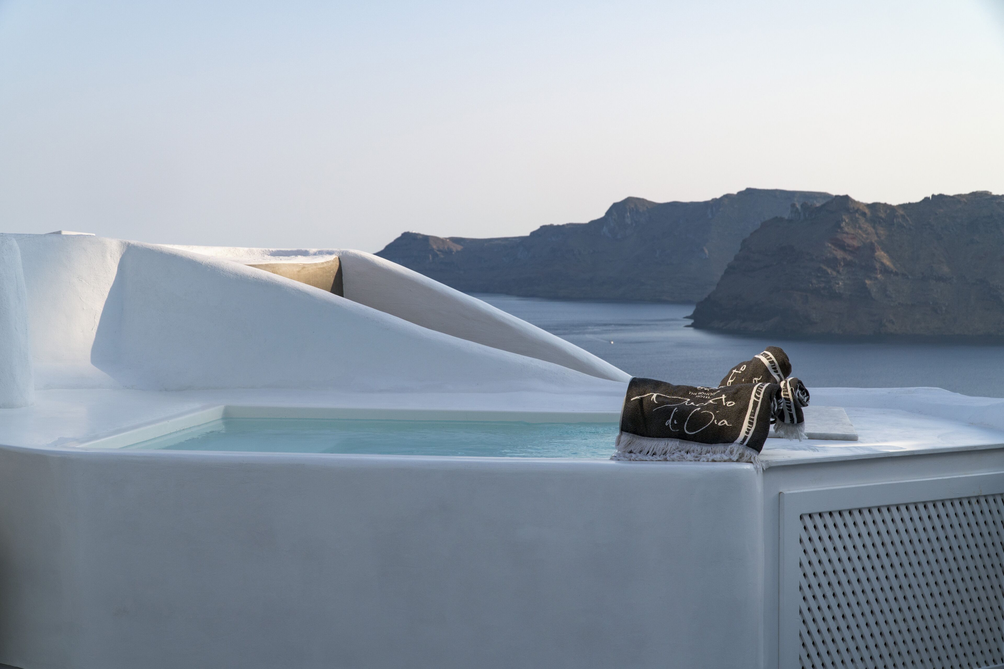 Una habitación moderna y minimalista con una bañera blanca grande y vistas al mar y a las montañas.