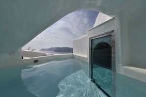 Uma piscina infinita moderna com vista clara para o mar e montanhas ao longe.