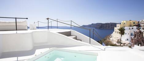 A rooftop pool with a clear view of the sea and coastal buildings.