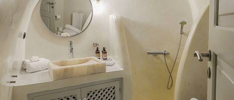 A compact bathroom with a sink, mirror, toilet, and shower.