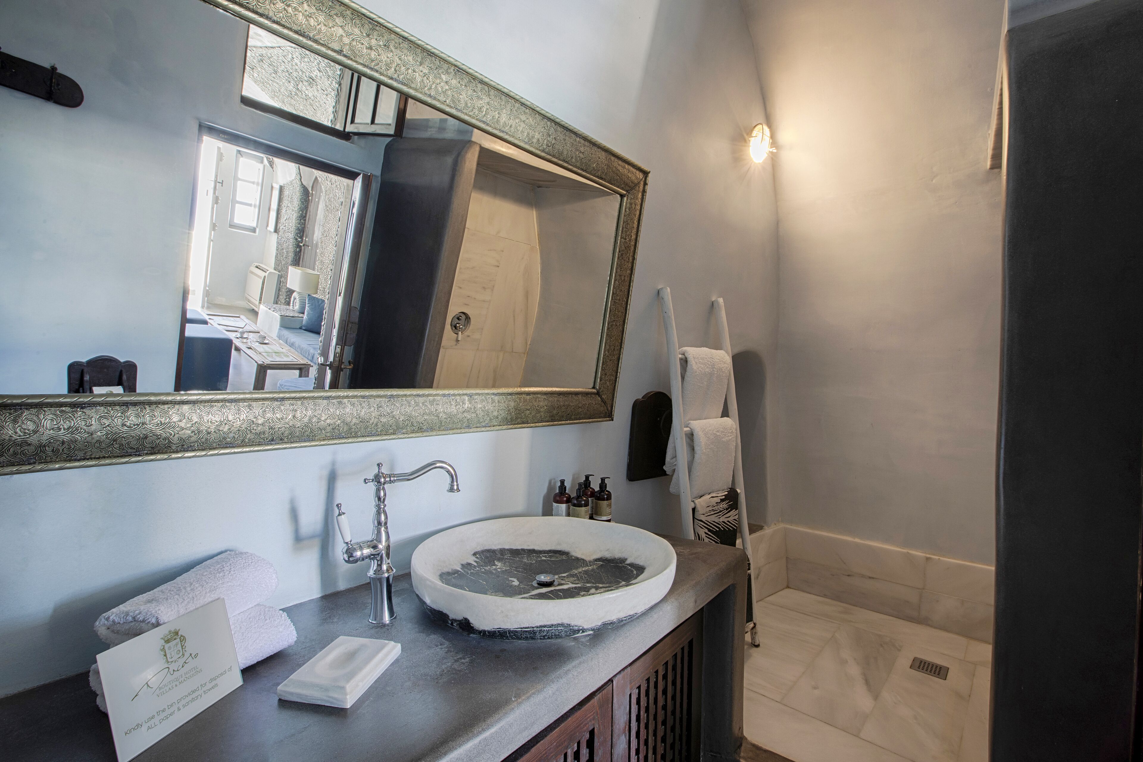 Een badkamer met een grote spiegel, een wastafel, een handdoek en een douchehoek.