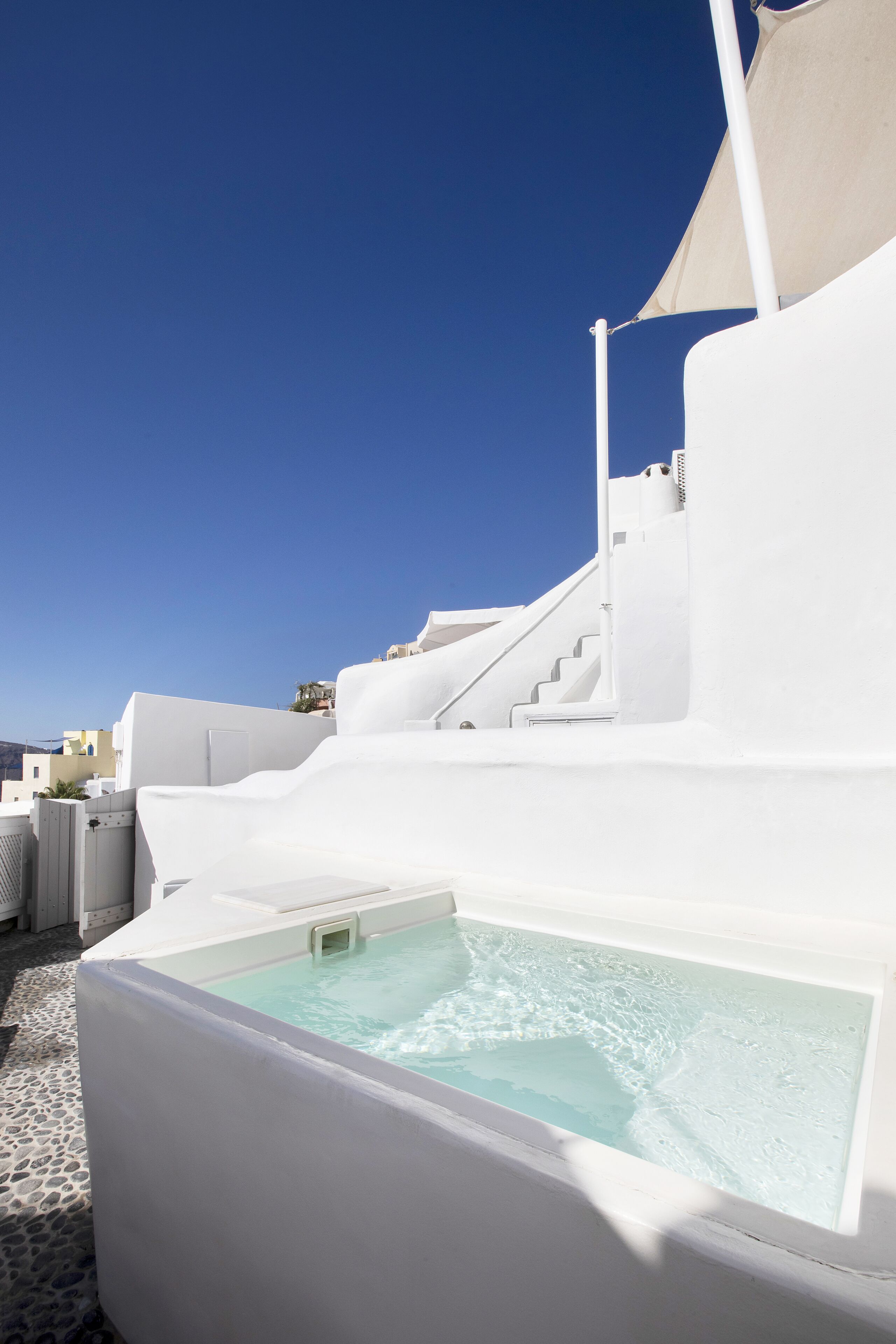A white building with a pool and steps leading up to a terrace.