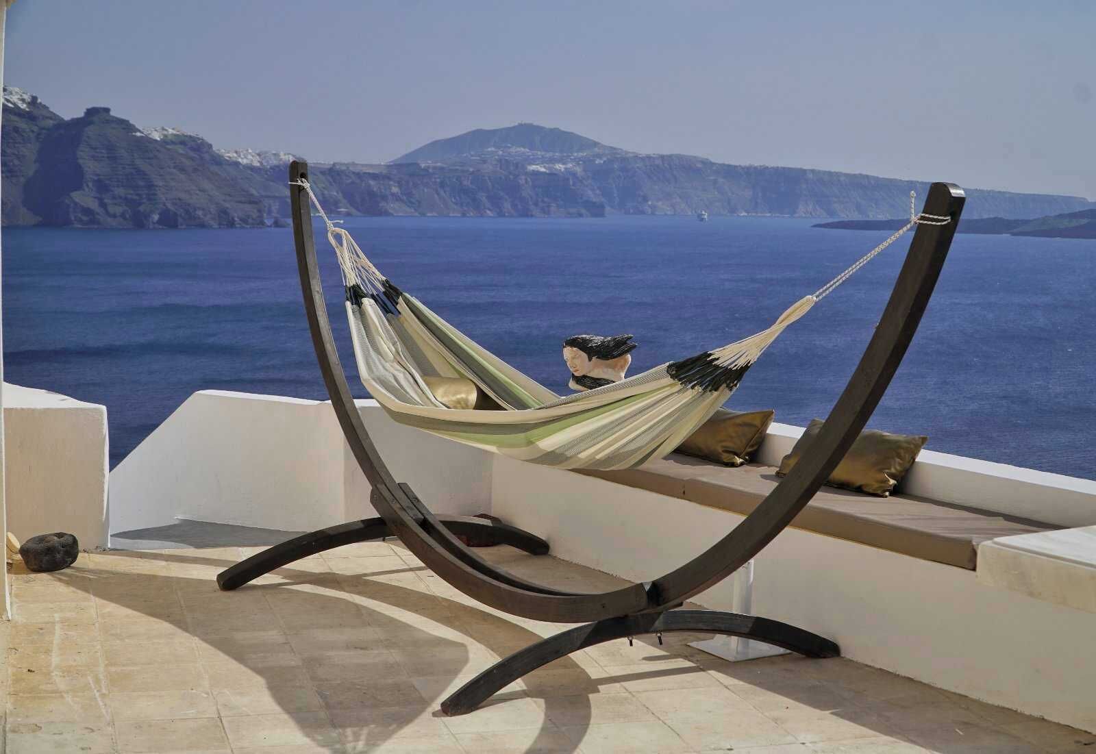 A hammock chair with a view of the sea and cliffs.