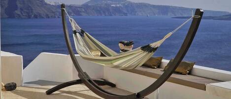 A hammock chair with a view of the sea and cliffs.