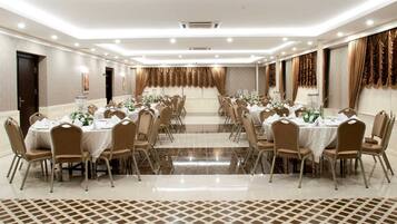 A banquet hall with tables set for dining, chairs, and a central aisle.