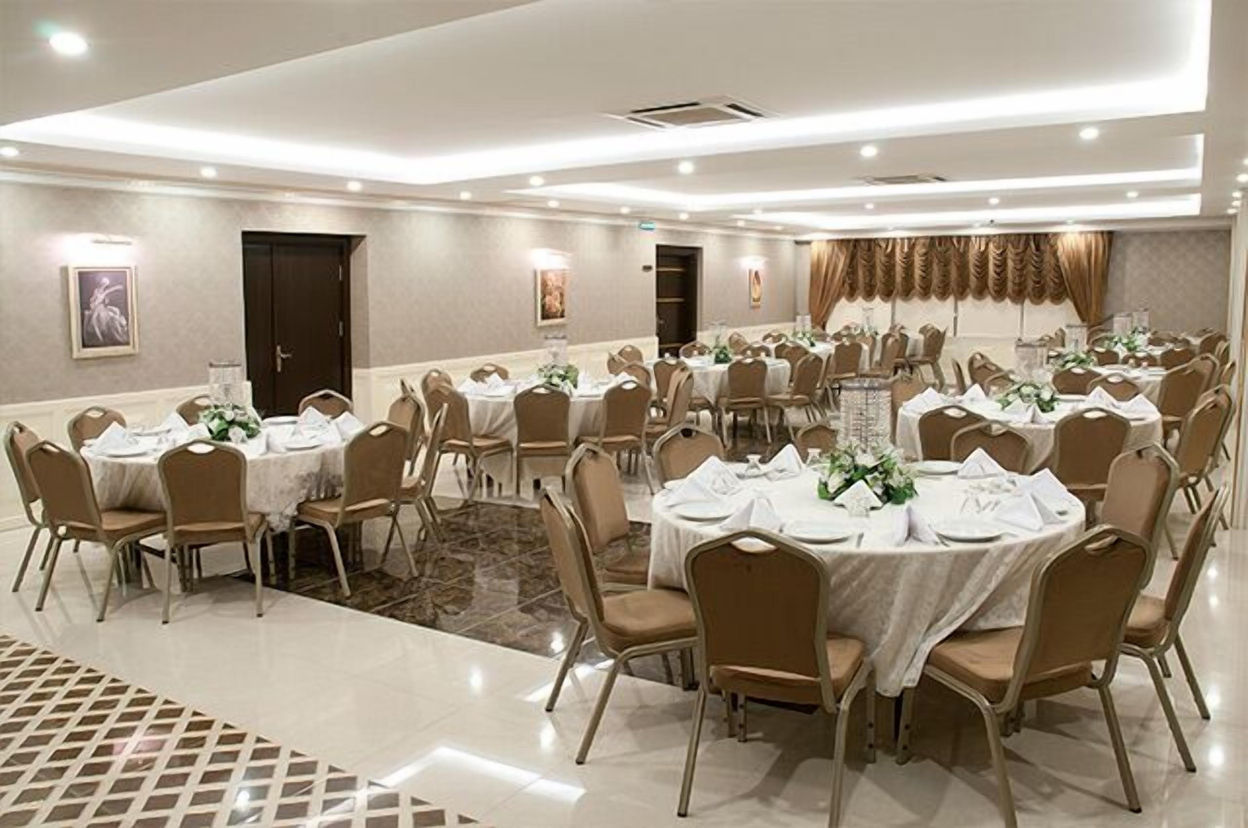 A banquet hall with round tables, beige chairs, and white tablecloths.