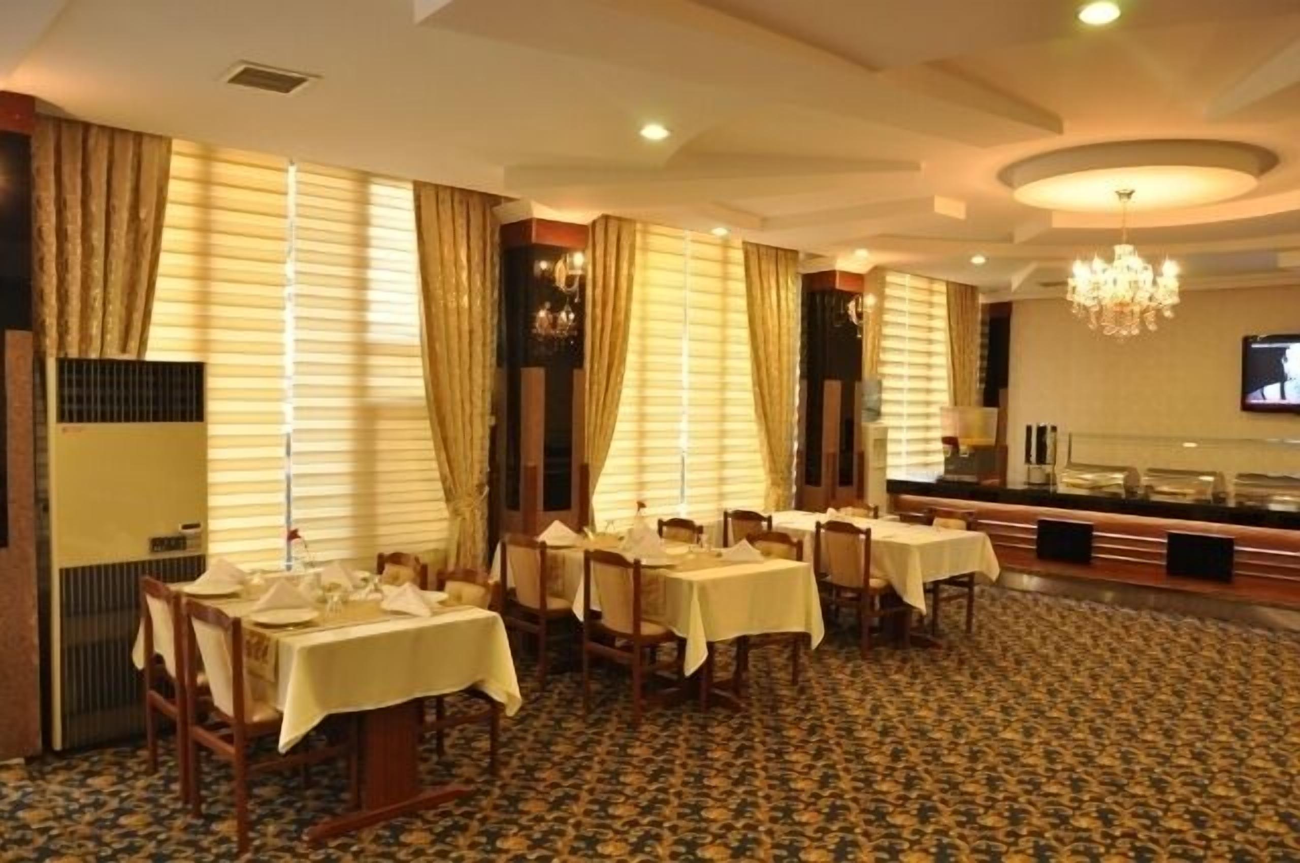 Un comedor con mesas dispuestas para el servicio, una barra de buffet y una pantalla de televisión en la pared.