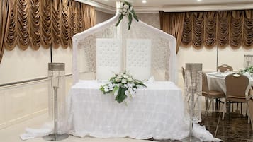 Decoración de boda con una cama con dosel, arreglos florales y una mesa con sillas.