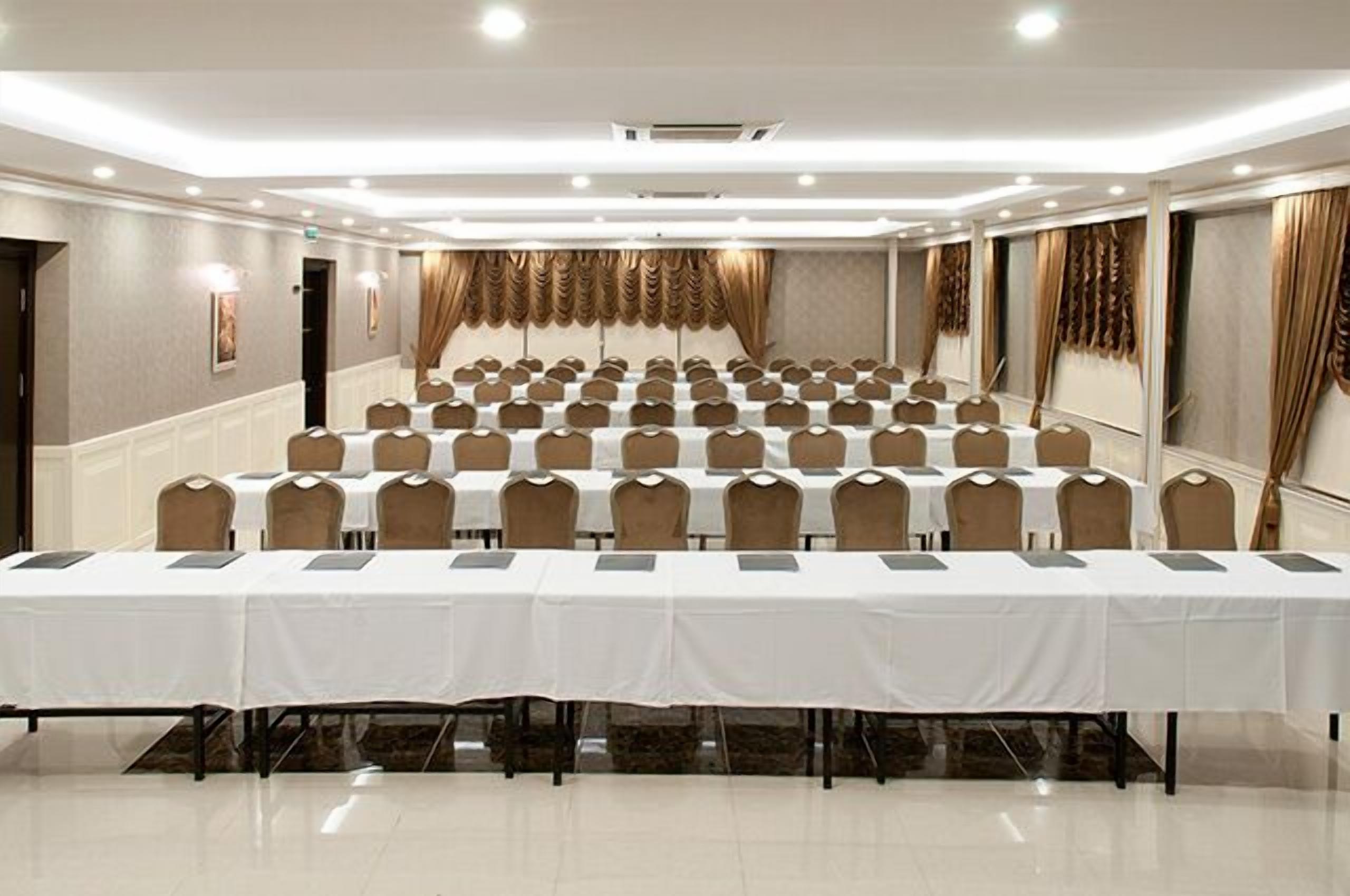 A conference room with multiple tables and chairs, arranged in rows.