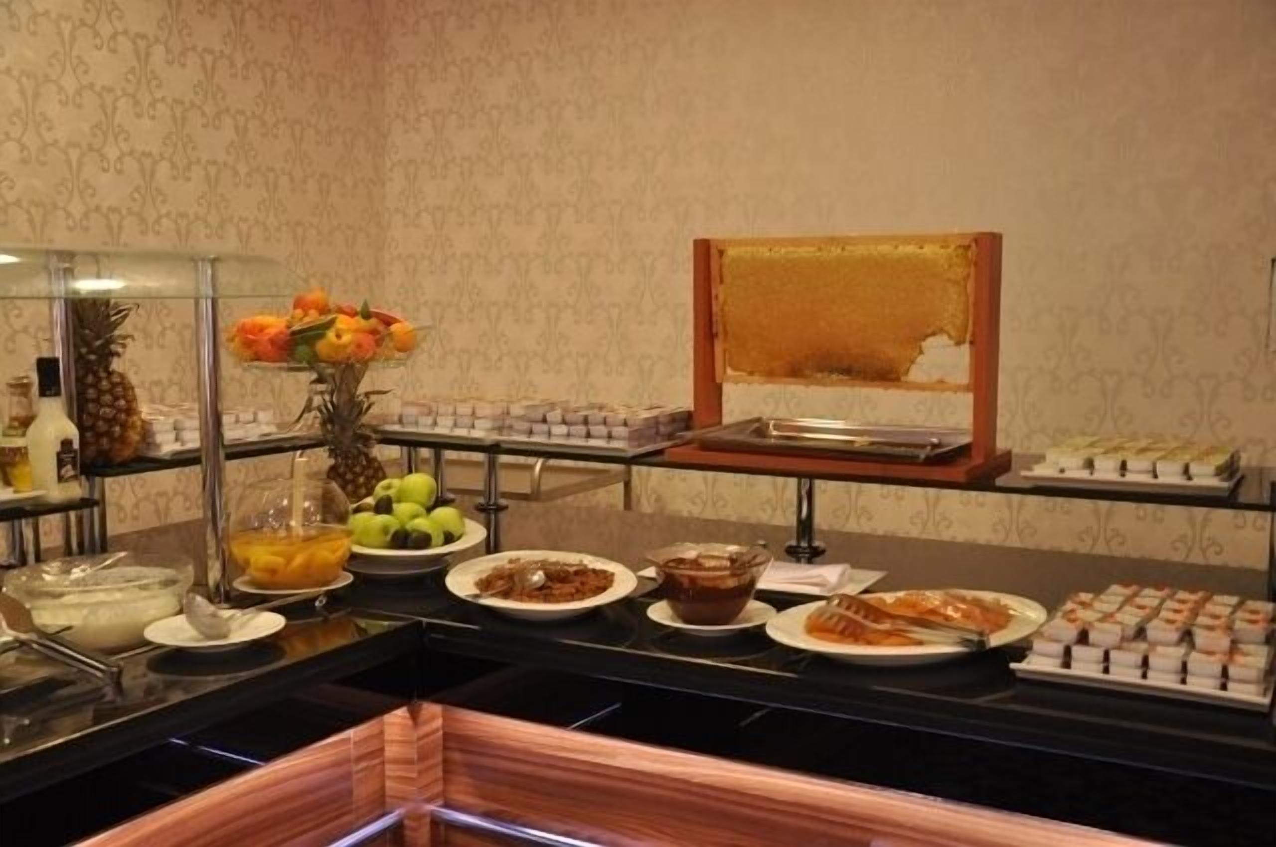 A buffet setup with various food items, including fruits, desserts, and beverages.