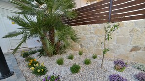 A landscaped garden with a palm tree, various shrubs, and flowers. - Villa Stella Apartments By Estia (Hersonissos)