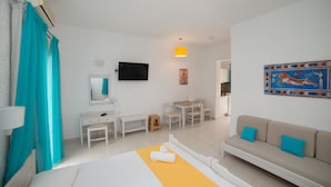 A hotel room with a bed, a desk, a chair, a sofa, a TV, and a painting on the wall. - Villa Stella Apartments By Estia (Hersonissos)