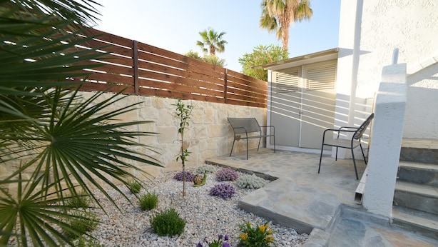 A patio with stone flooring, a wooden fence, and a seating area with chairs. - Villa Stella Apartments By Estia (Hersonissos)