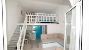 A modern interior with a staircase leading to a loft bedroom, a sofa, and a dining area. - Villa Stella Apartments By Estia (Hersonissos)