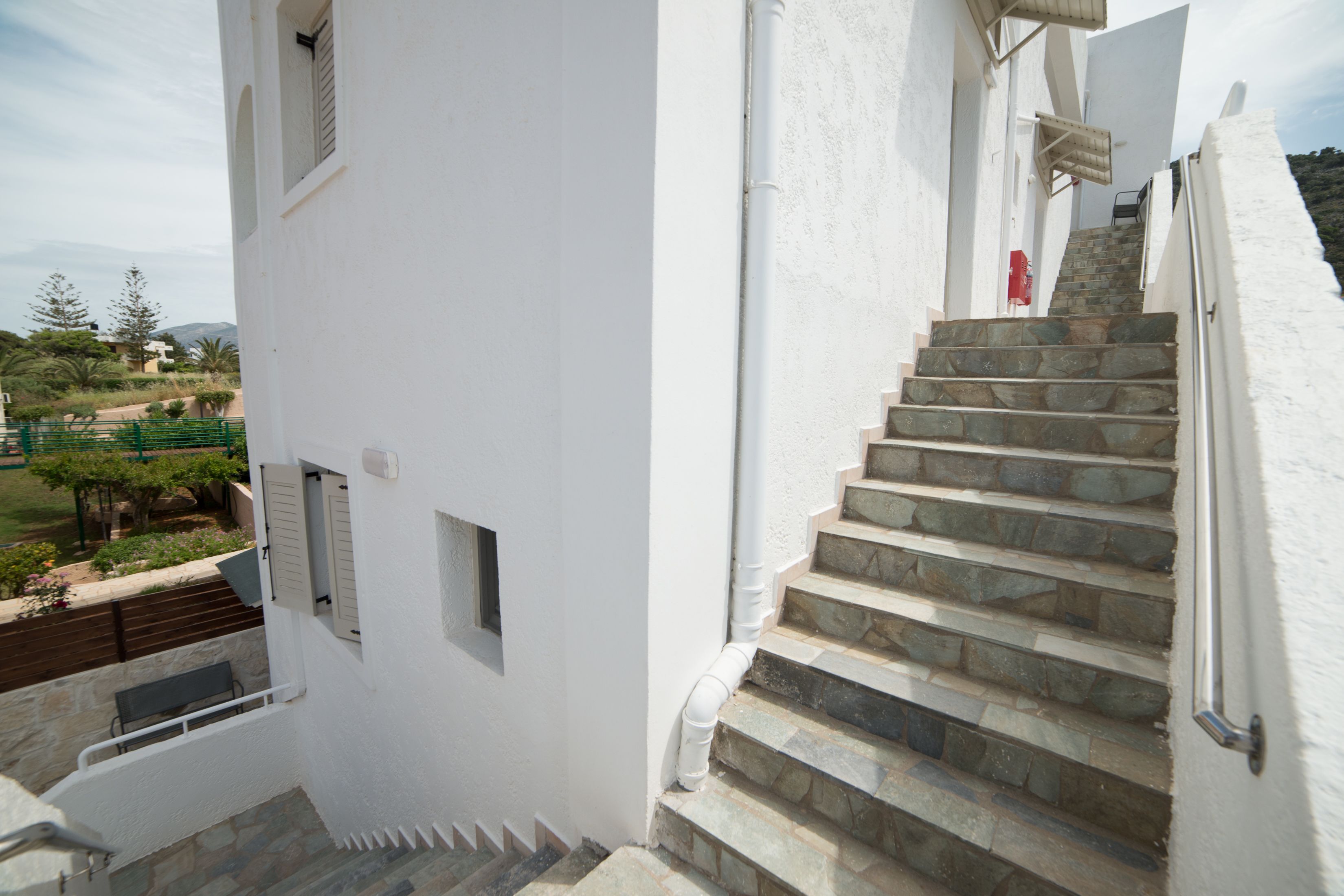 A white building with a stone staircase leading to a balcony.