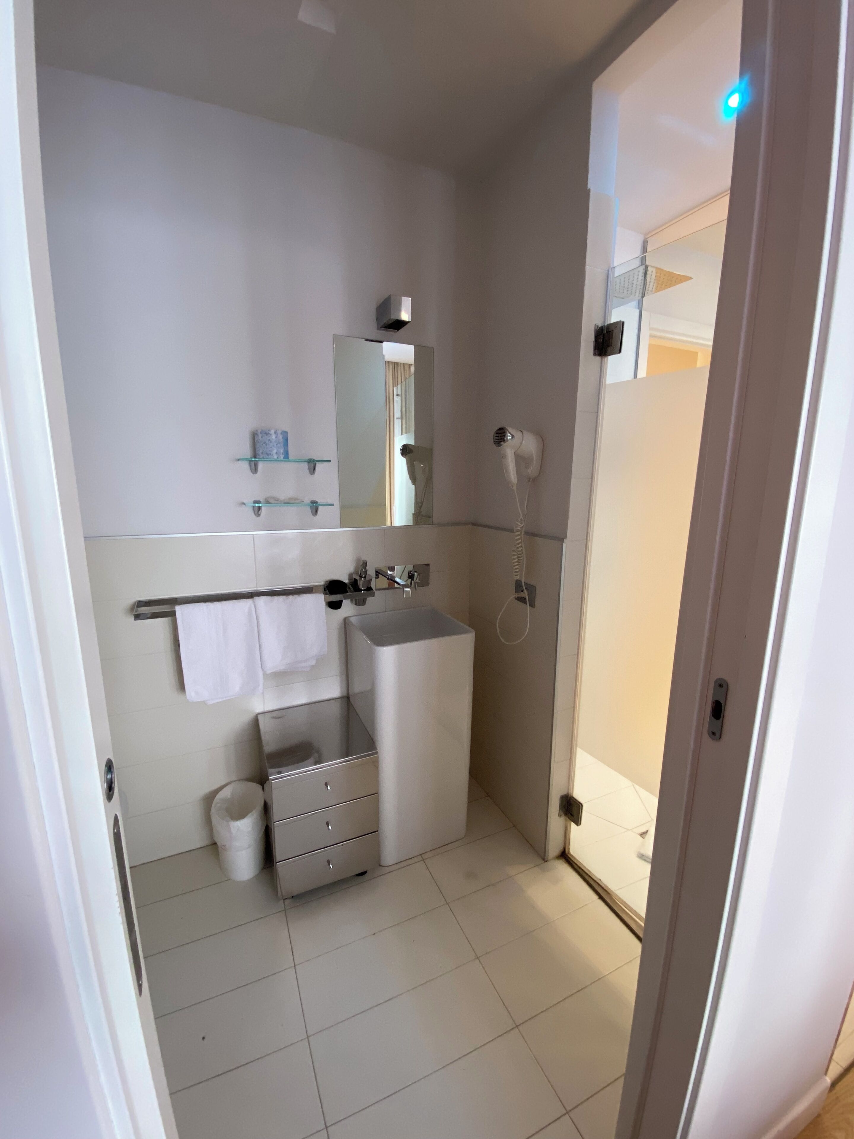 Une salle de bain moderne équipée d’un lavabo, d’un miroir, d’un porte-serviettes et d’un sèche-cheveux.