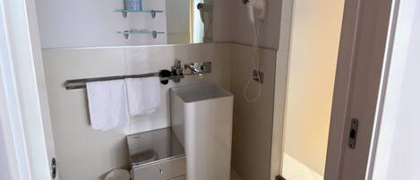 Une salle de bain moderne équipée d’un lavabo, d’un miroir, d’un porte-serviettes et d’un sèche-cheveux.
