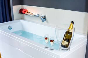 Una vasca da bagno con una bottiglia di champagne e due bicchieri.