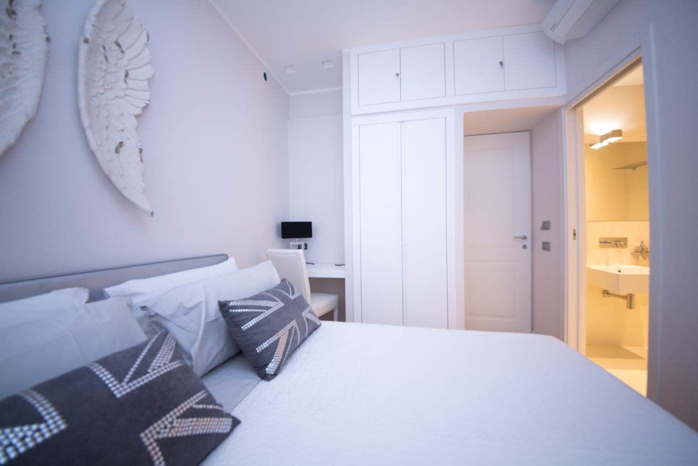 A modern hotel room with a large bed, a desk, and a walk-in closet.