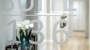 Un pasillo con mostrador de recepción, un letrero que dice 'Luxury Suites 13-16' y un jarrón decorativo con flores.