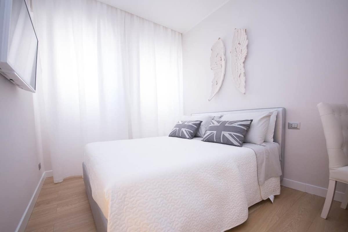 Une chambre à coucher comprenant un lit, une chaise et une œuvre d’art accrochée au mur.