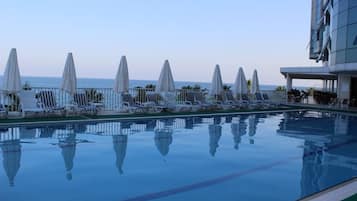 Piscine couverte, piscine extérieure, parasols de plage, chaises longues