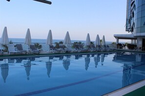 Alberca techada, alberca al aire libre y sombrillas en la alberca