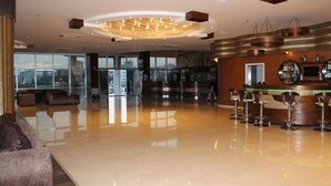 Un vestíbulo amplio con zona de bar, asientos y grandes ventanales con vistas a la ciudad.