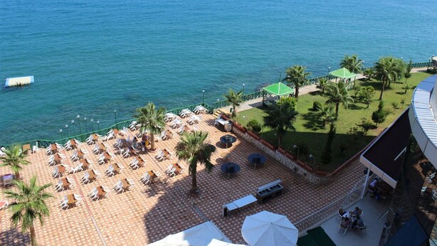 Un hotel frente a la playa con un patio, palmeras y vistas al mar.