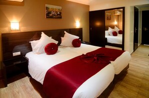 Habitación de hotel con una cama grande, dos mesitas de noche, un espejo y un cuadro en la pared.
