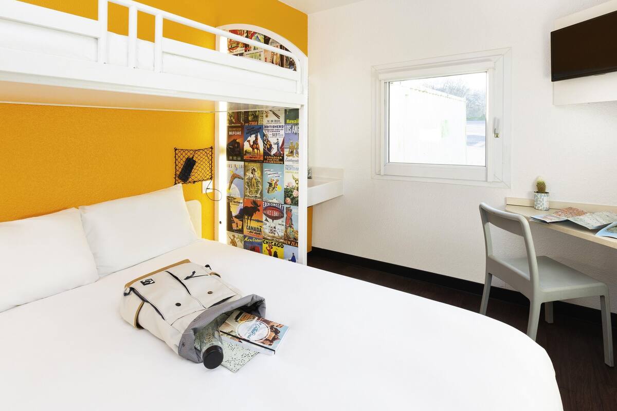 A room with a bunk bed, a desk with a chair, a window, and a wall with a map.
