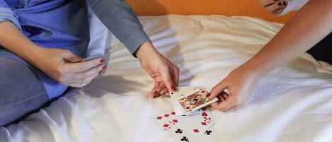 Una persona sosteniendo cartas de juego sobre una cama.