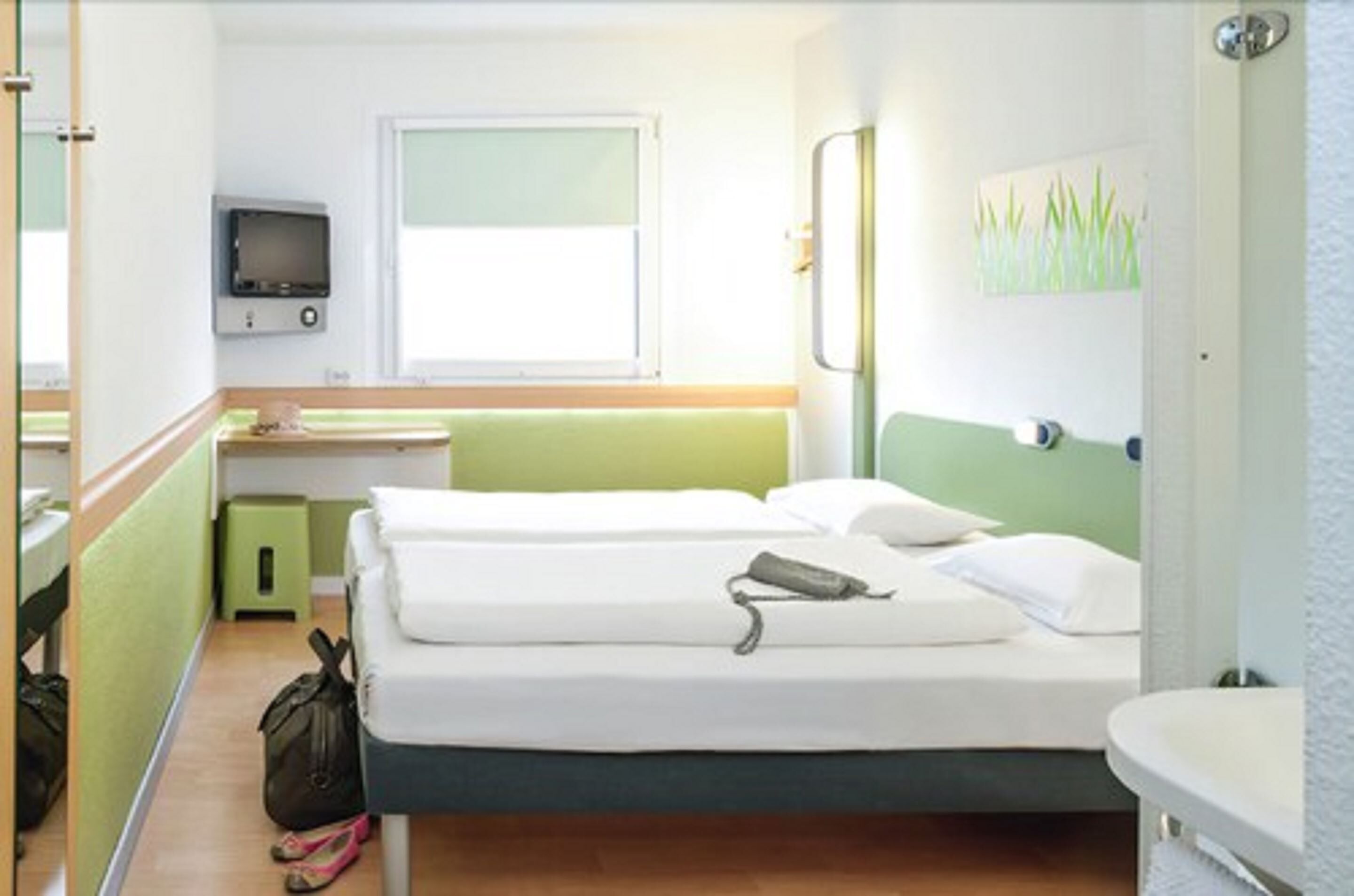 A hotel room with a bed, a small desk, a television, and a bathroom.