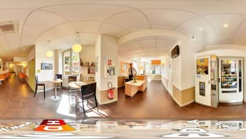 Un hall d’hôtel spacieux comprenant un comptoir d’accueil, un espace salon et des distributeurs automatiques.