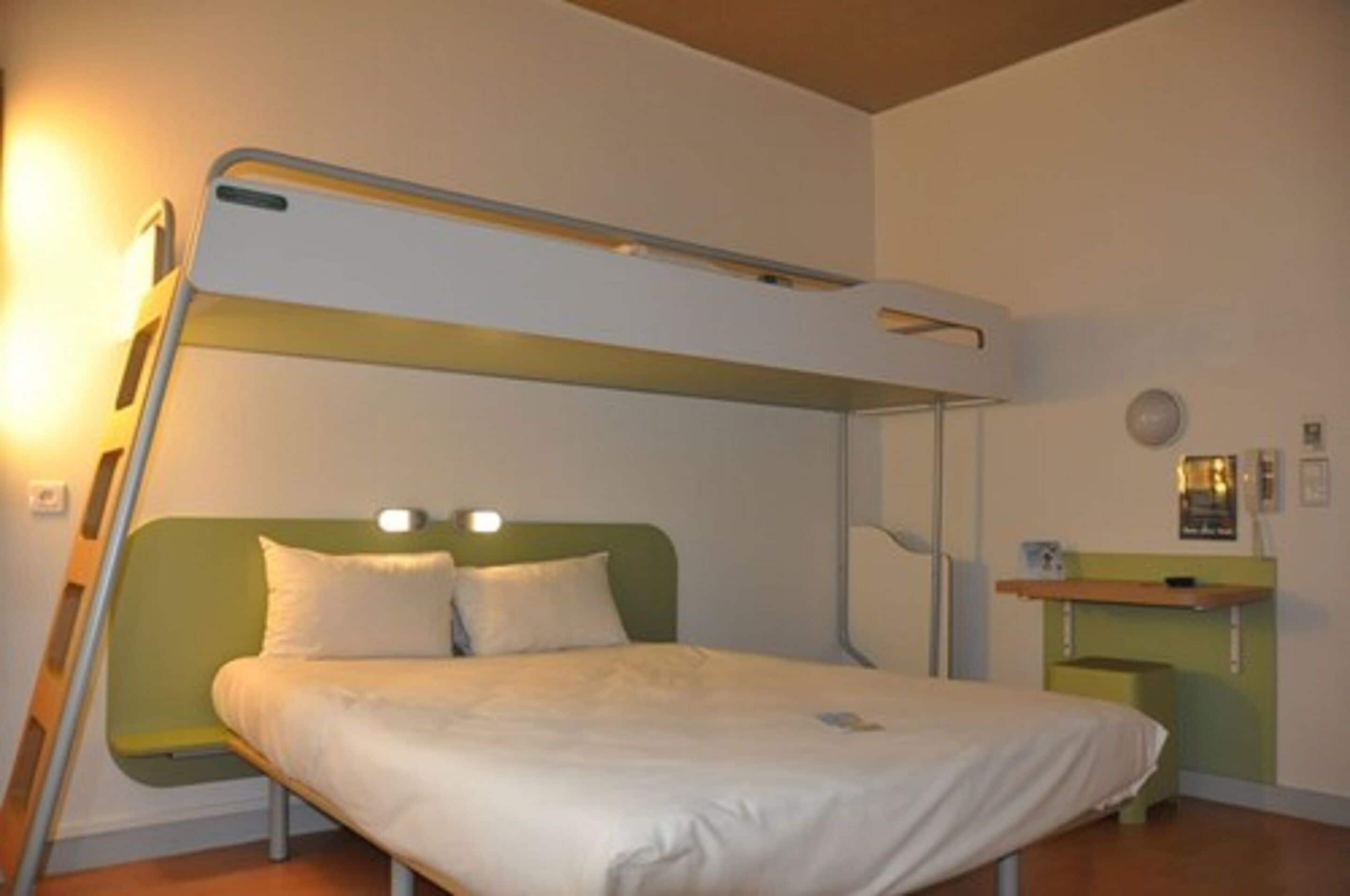 A bunk bed with a green headboard and a bedside table with a lamp.