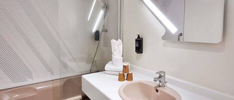 Un baño moderno con un lavabo blanco, un espejo y una ducha.