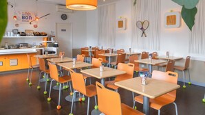 Interior de un restaurante con mesas, sillas, una barra y un reloj en la pared.
