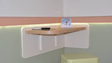 A reception desk with a signboard, a small table with a bowl, and a yellow stool.