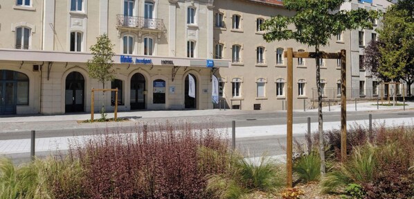 Un hôtel à la façade classique, doté de fenêtres en arc de cercle et d’une enseigne indiquant qu’il s’agit d’un hôtel.