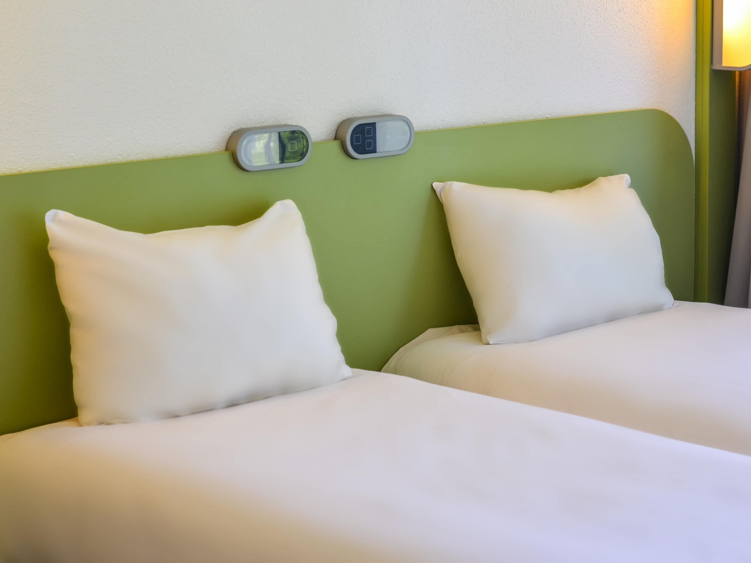 A twin room with two beds, a green headboard, and bedside lamps.