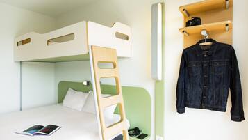 Una cama litera con escalera, una mesita de noche con un libro, auriculares, un teléfono inteligente y un perchero con una chaqueta vaquera.