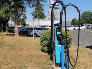 Uma estação de carregamento para veículos elétricos azuis, com sinalização indicando carregamento e descarregamento.