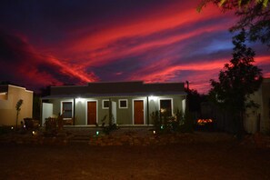 A house with a stone foundation, multiple doors, and a well-lit entrance. - Travellers Rest (Prince Albert)
