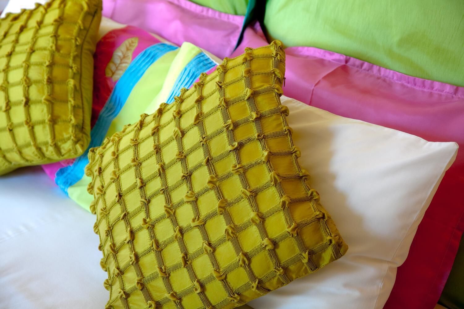 A bed with a white mattress and pillows in various colors.