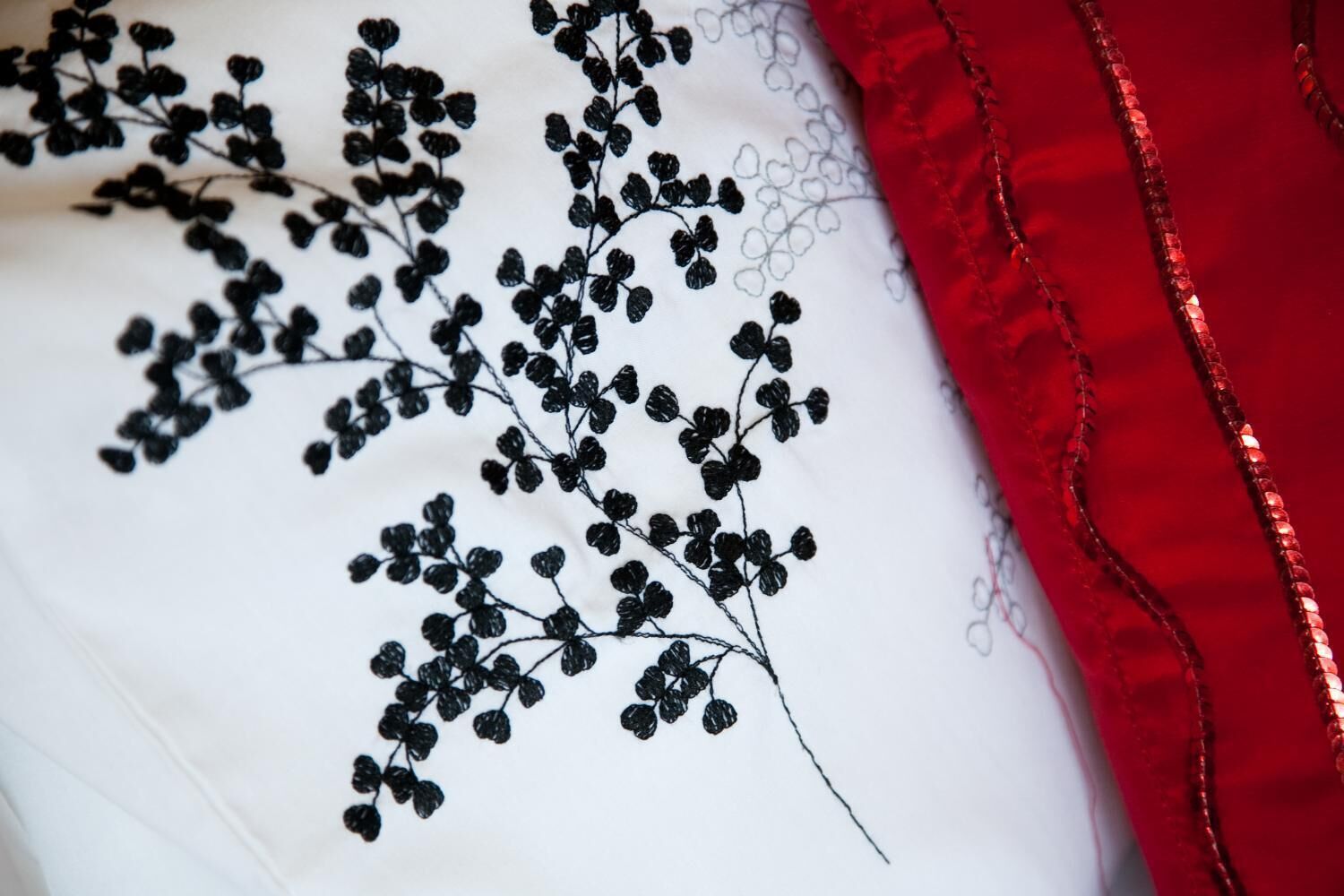 A white fabric with black embroidery of a floral pattern.