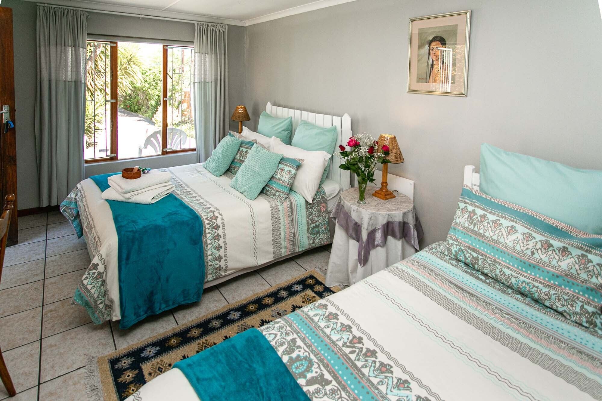 Un dormitorio con dos camas, una mesita de noche con una lámpara y un cuadro en la pared.